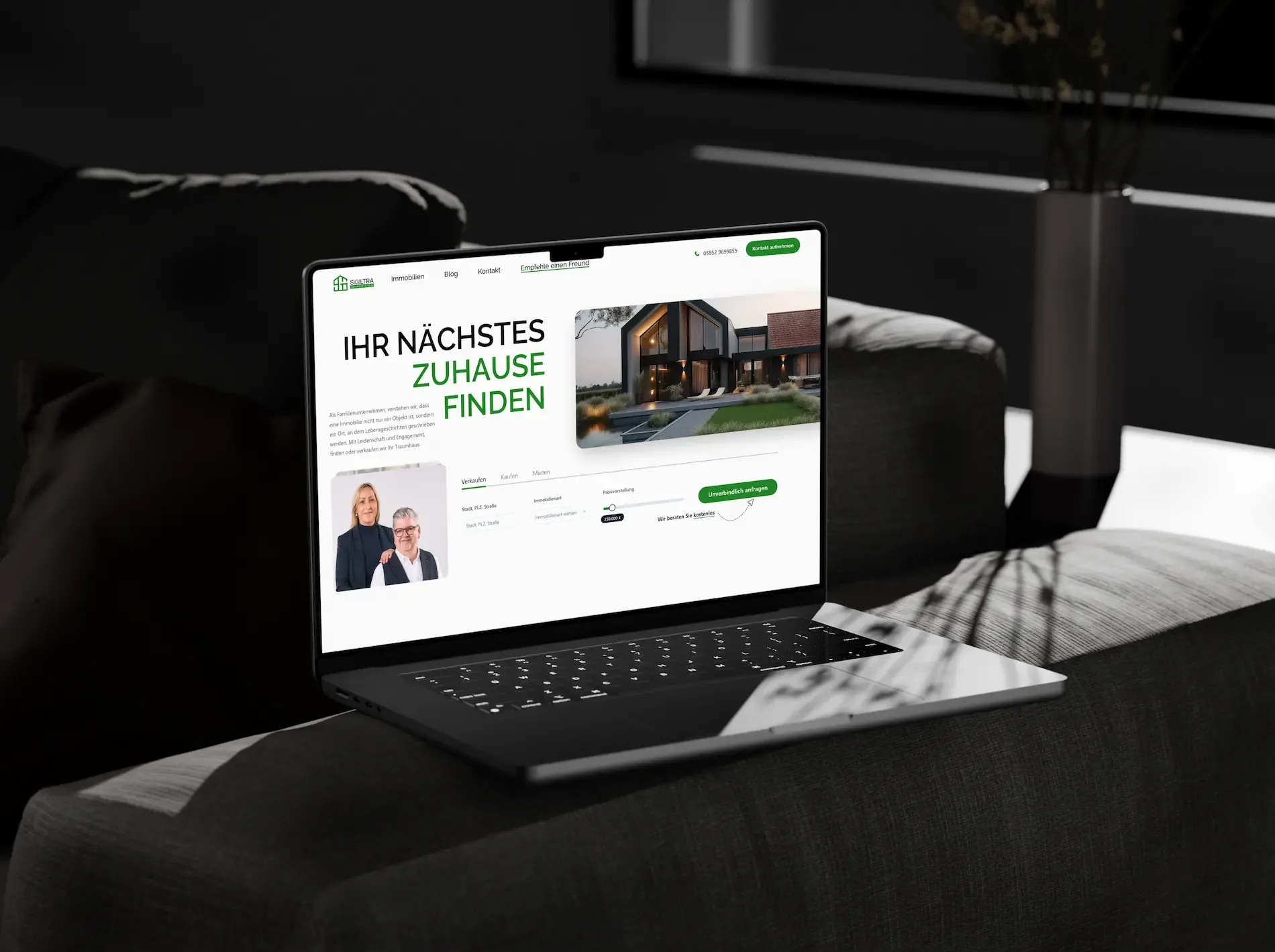 Ein Laptop auf einer schwarzen Couch zeigt die Startseite von sigiltra-immobilien.de